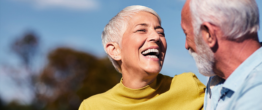Senior man and woman smiling outside.