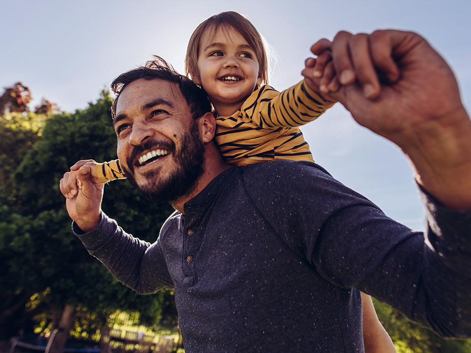 A father giving his daughter a piggy-back ride.
