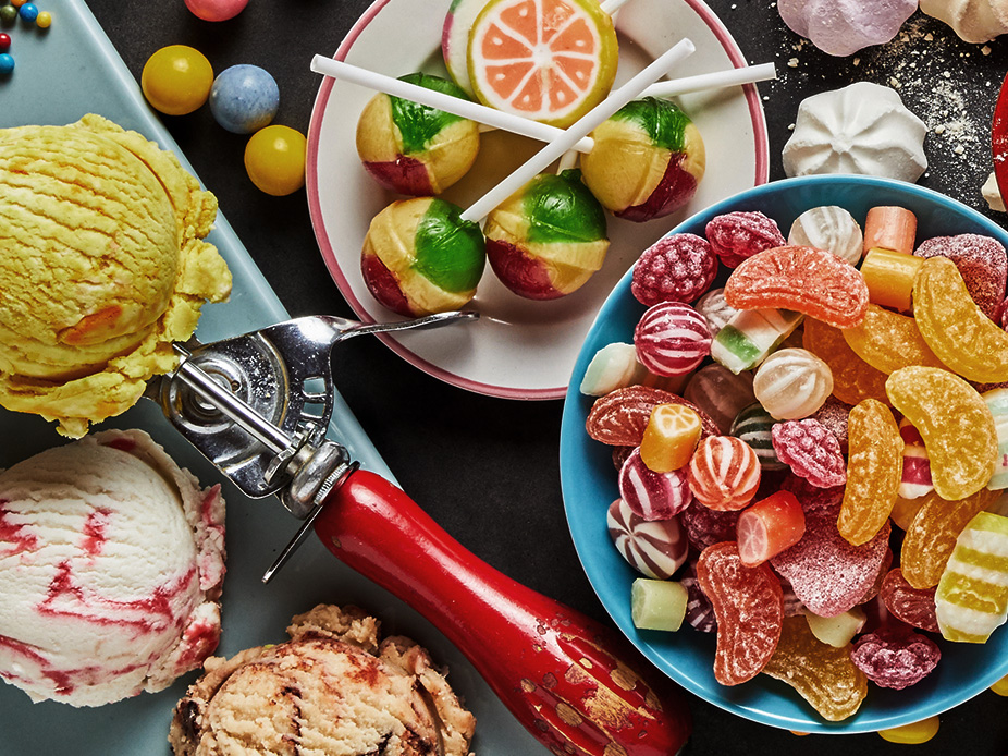 Chewy candy, ice cream scoops, lollipops, and other sweets on a table.
